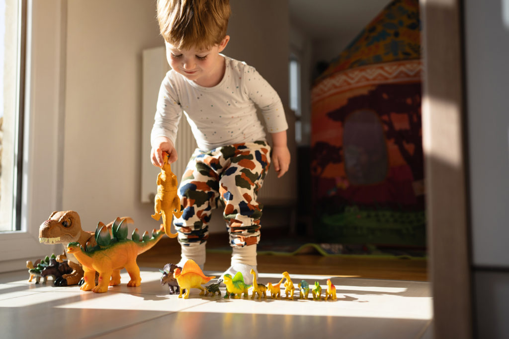 Barn som leker med dinosaur-figurer